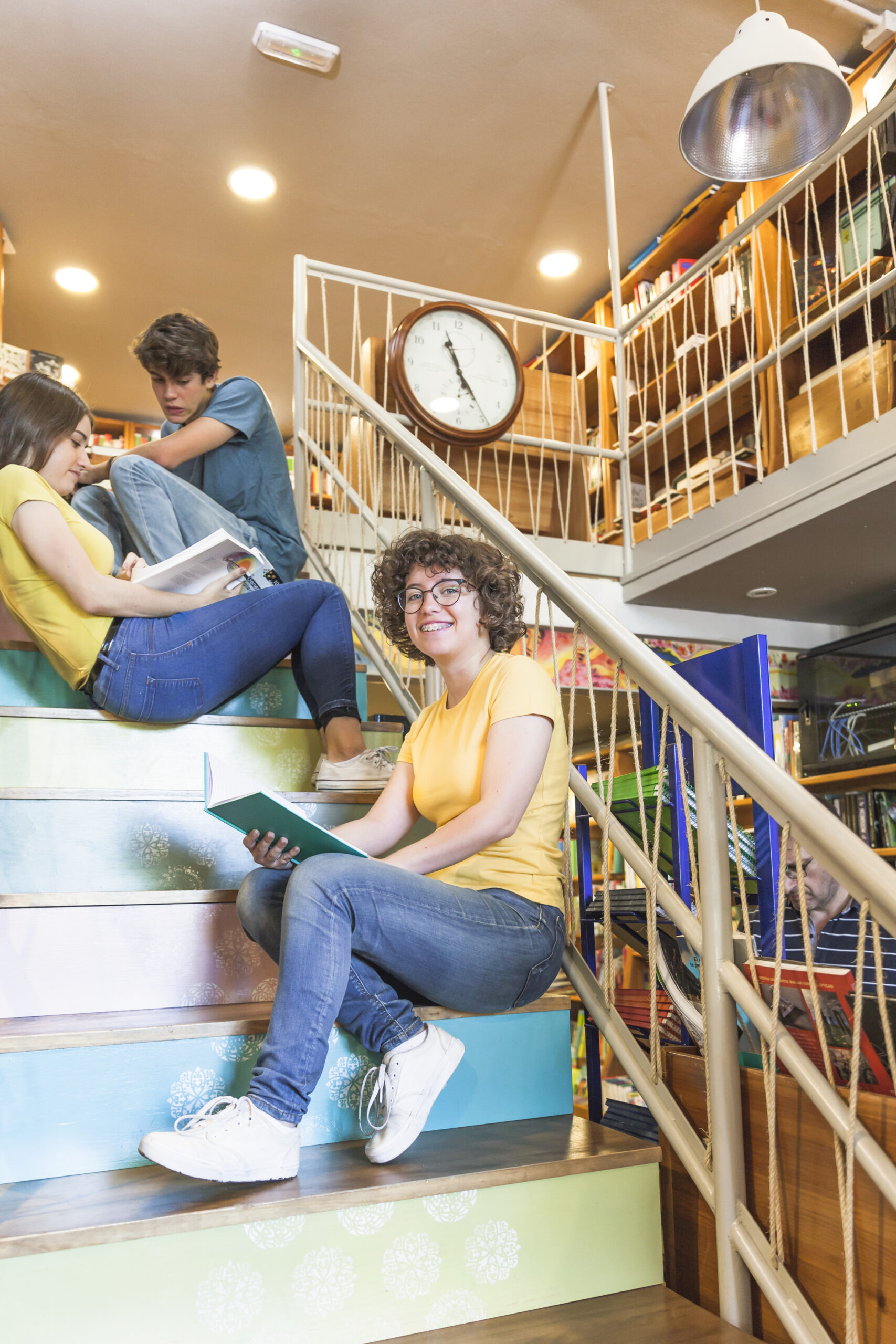 cheerful-teen-girl-with-book-sitting-near-friends